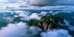 海角社区视频旅行见闻专区，旅行博主站在云雾缭绕的山顶拍摄风景视频，壮阔自然风光